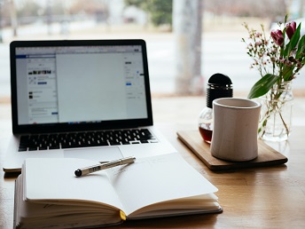 laptop computer with open book and coffee cup