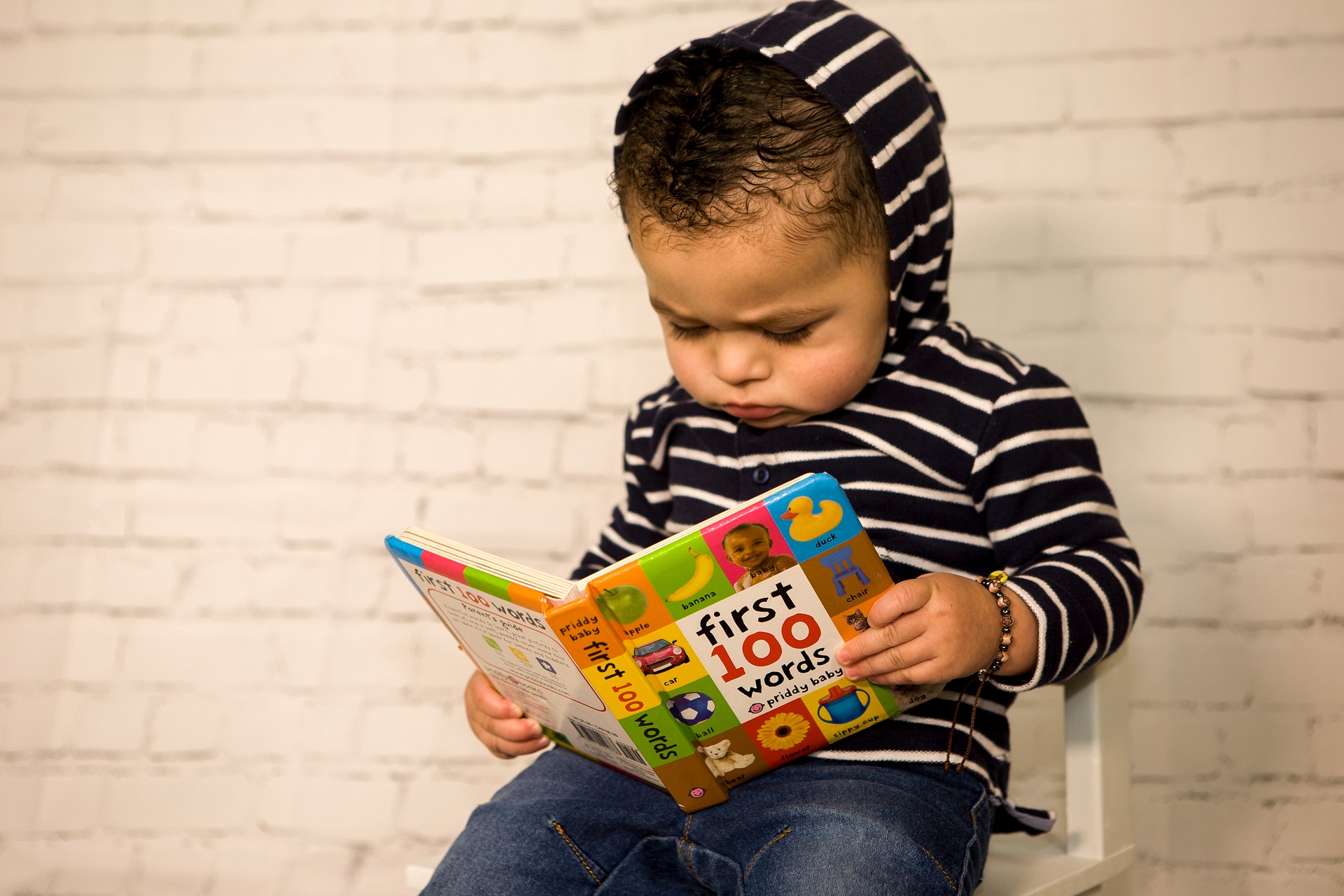 toddler reads a book of 100 first words.