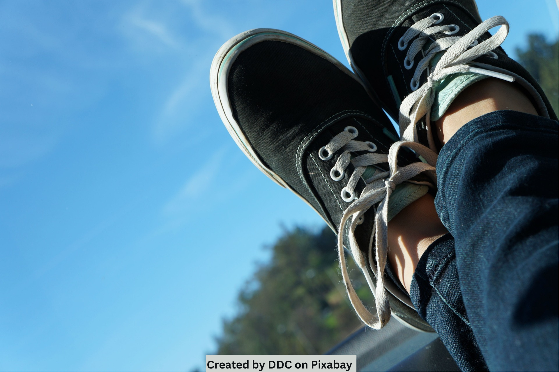 crossed legs wearing tennis shoes with horizon in the background.