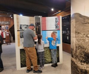 An adult and two children look at an Museum exhibit.